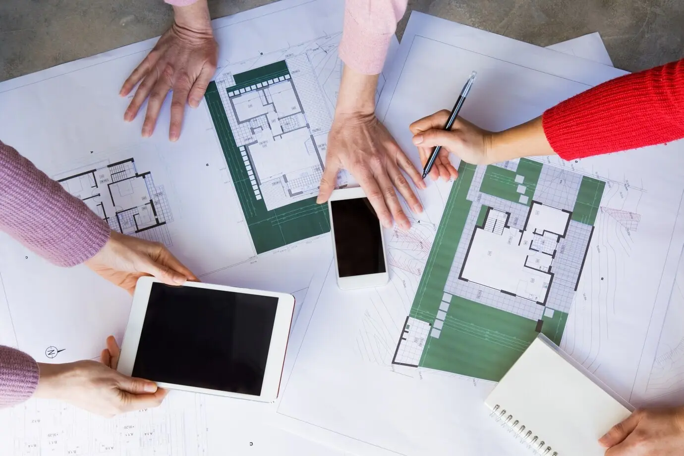 Nahaufnahme von Architekten, die mit Zeichnungen arbeiten und Gadgets benutzen.